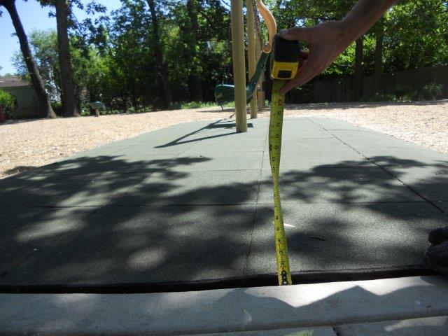 The change in level from the concrete path to the tile surface is measured with a tape measure.