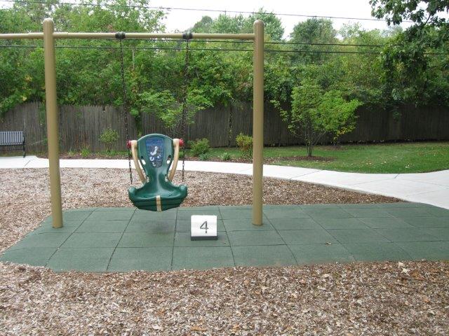 A hard-back swing over a rubber tile surface bordered with engineered wood fiber.